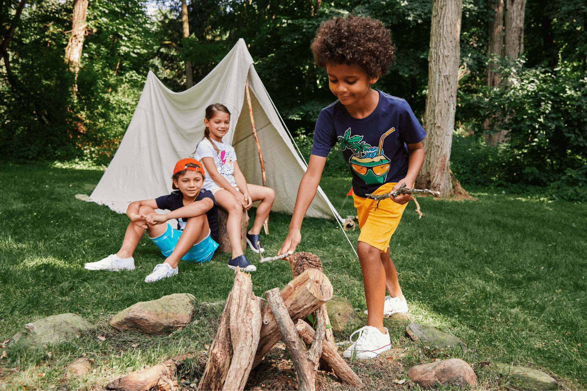 Kids having fun at summer camp, styling playful outfits by a campfire in a wooded area.