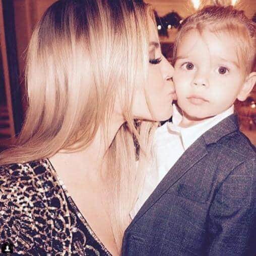 Khloe Kardashian kisses her nephew Mason, dressed stylishly in a suit, showcasing playful bonding and classy kids' fashion.