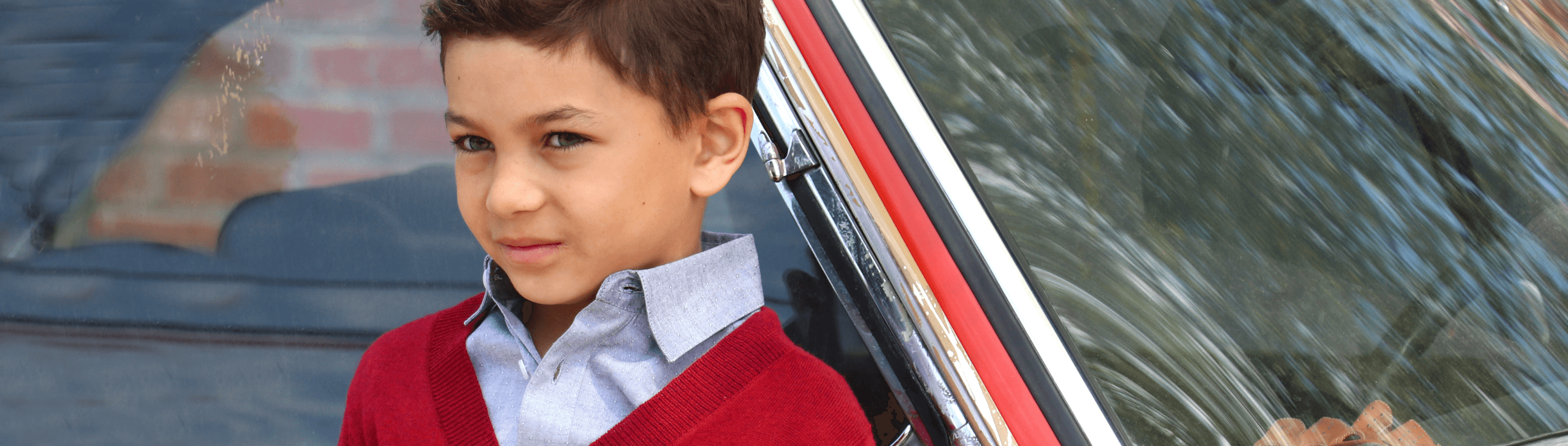 Stylish boy in a cozy red cardigan paired with a crisp shirt, embodying modern kids fashion vibes.