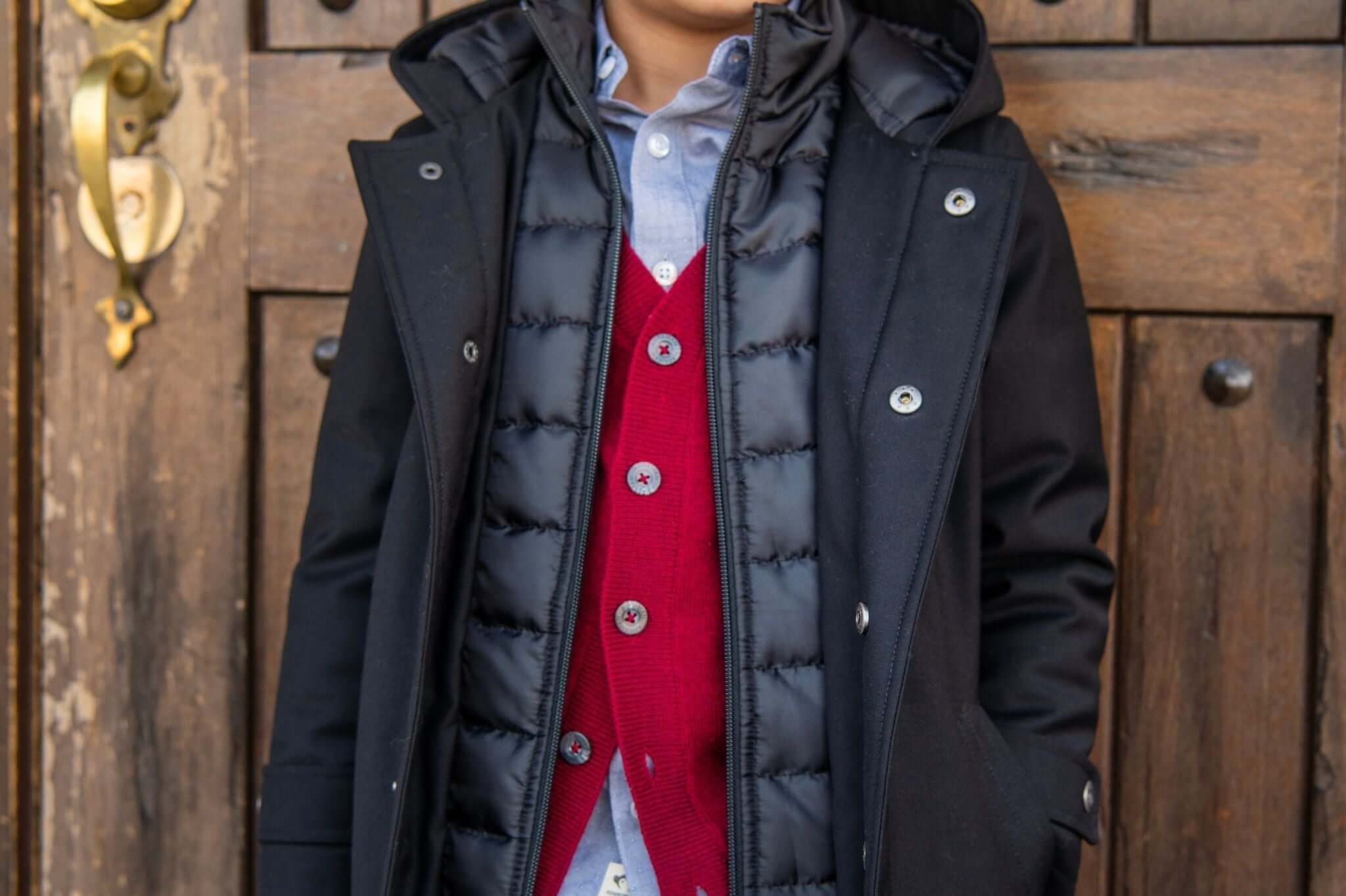 Stylish boy in a cozy black parka layered over a red vest, showcasing trendy winter formal fashion.