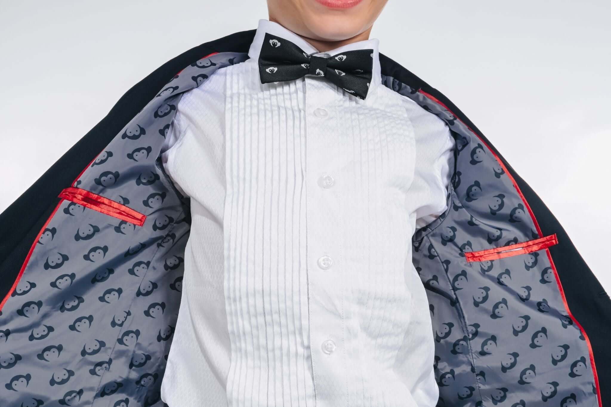 Stylish kid wearing a tuxedo with a playful penguin-lined interior, ready for a special event.