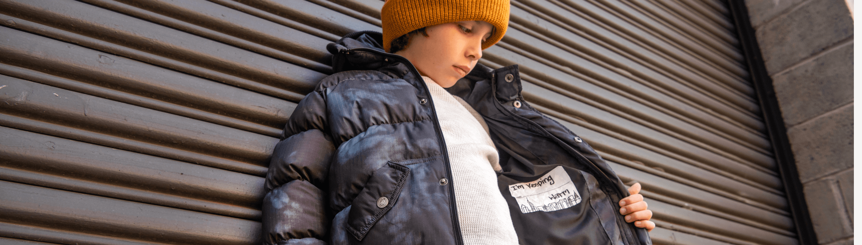 Stylish boy in a puffer jacket and bright beanie, showcasing modern winter fashion for kids.