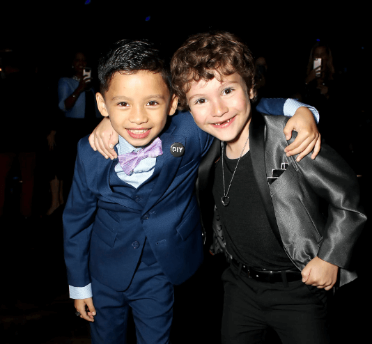 Two stylish boys in dapper suits pose playfully together, showcasing kids' fashion and fun styling tips.