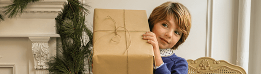 Stylish child holding a wrapped gift, embodying modern holiday cheer and thoughtful non-toy gift ideas for kids.