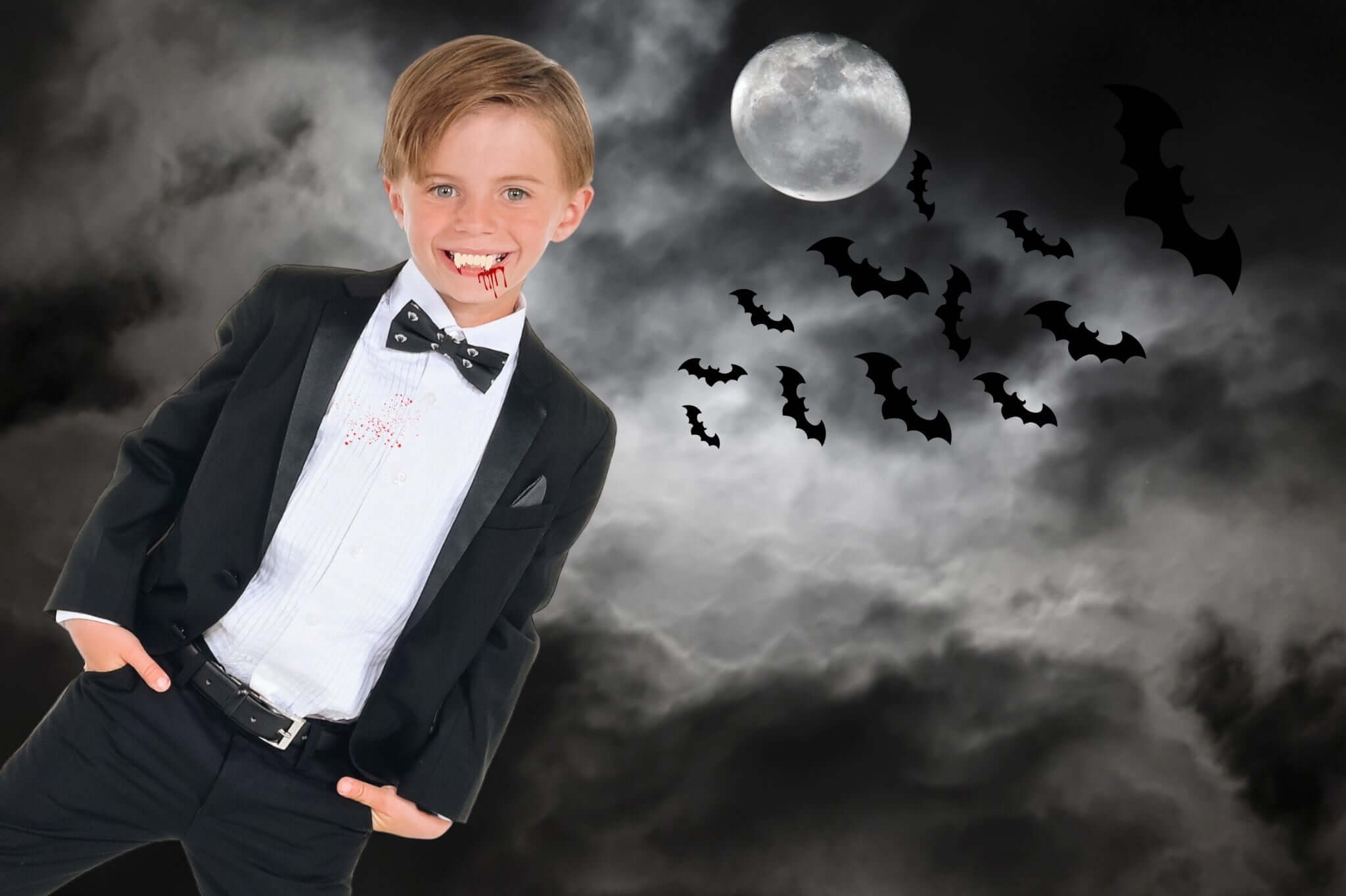 Charming boy in a classy suit with vampire-themed costume for Halloween, surrounded by bats and a full moon.