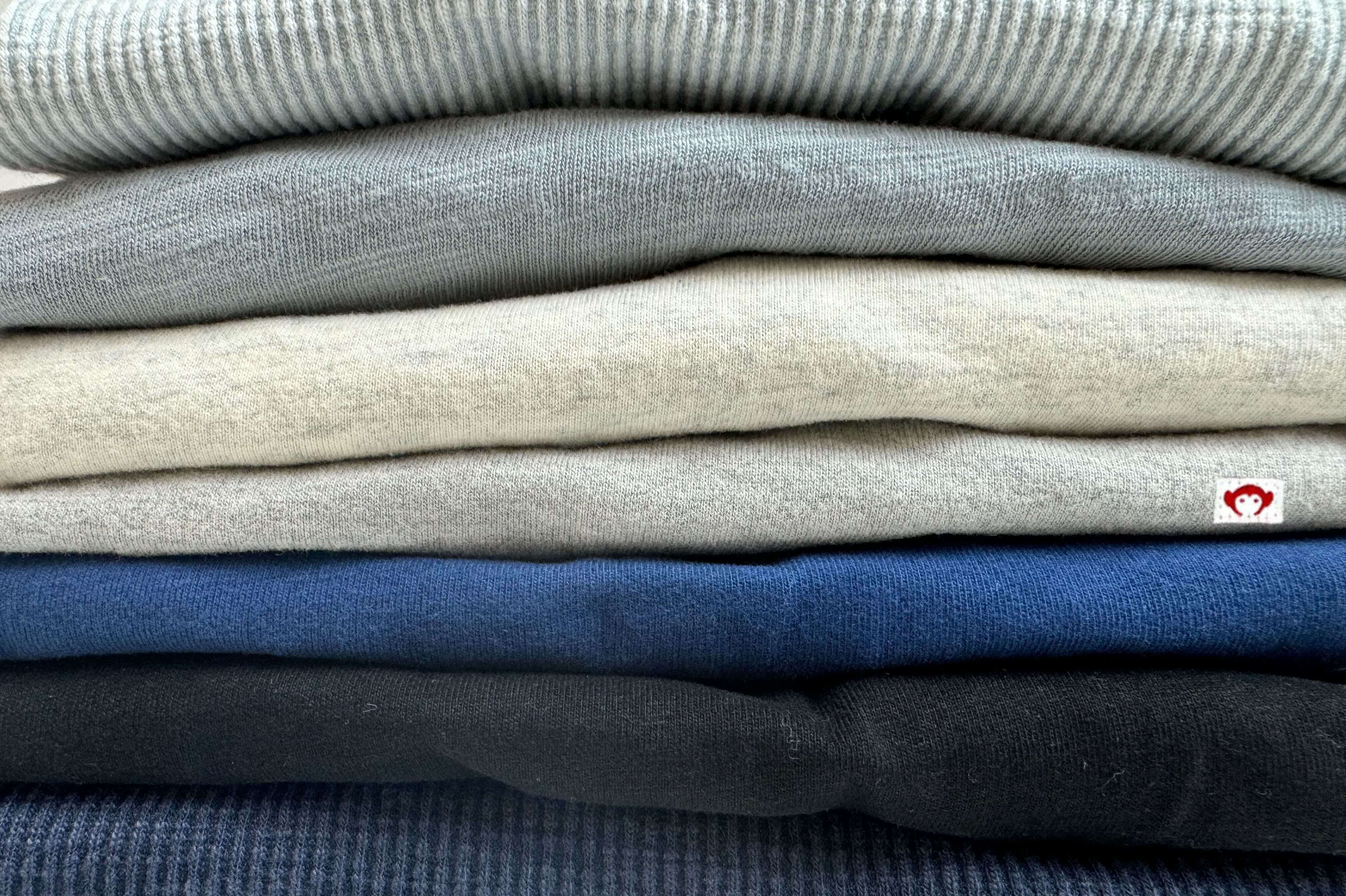 A stylish stack of soft, cozy sweaters in muted tones, perfect for dressing kids with sensitive skin.