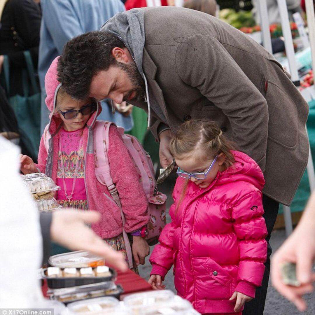 Ben Affleck interacts with daughters at a market, showcasing stylish kids' winter wear, including Violet's vibrant pink Appaman coat.