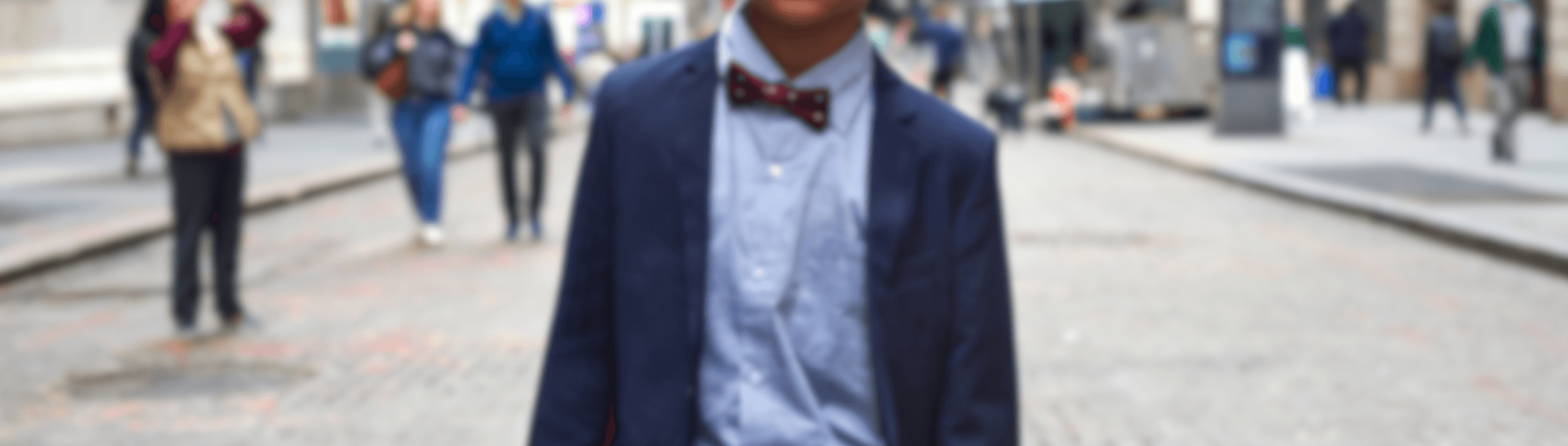 A stylish young boy in a suit and bow tie confidently enjoys urban life, showcasing contemporary kids fashion.