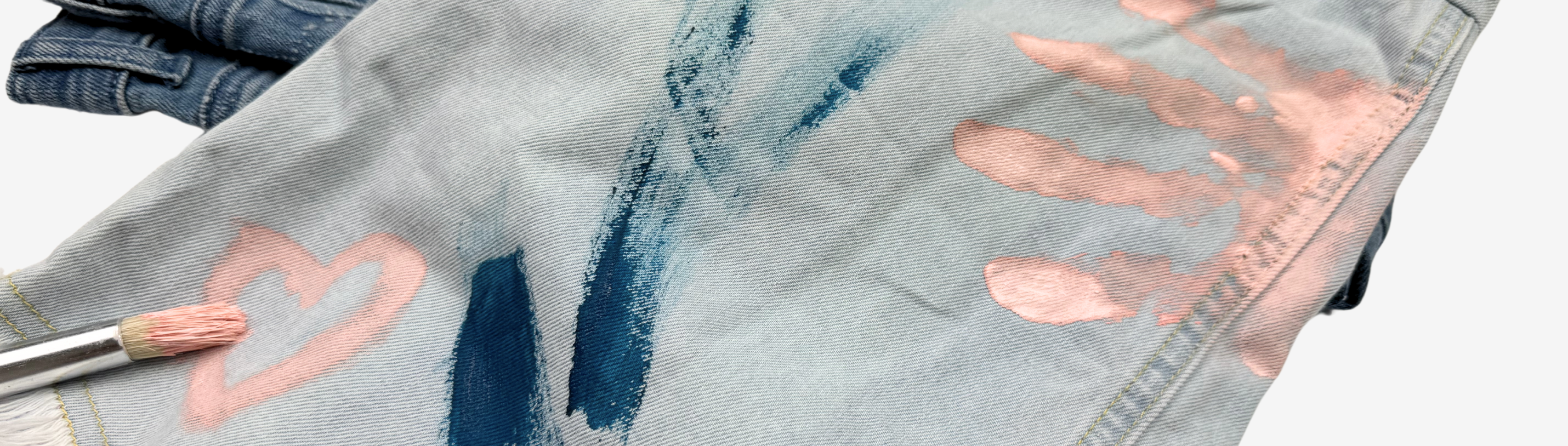 Close-up of paint-stained denim, showcasing vibrant brush strokes and playful handprints from creative kids' art projects.