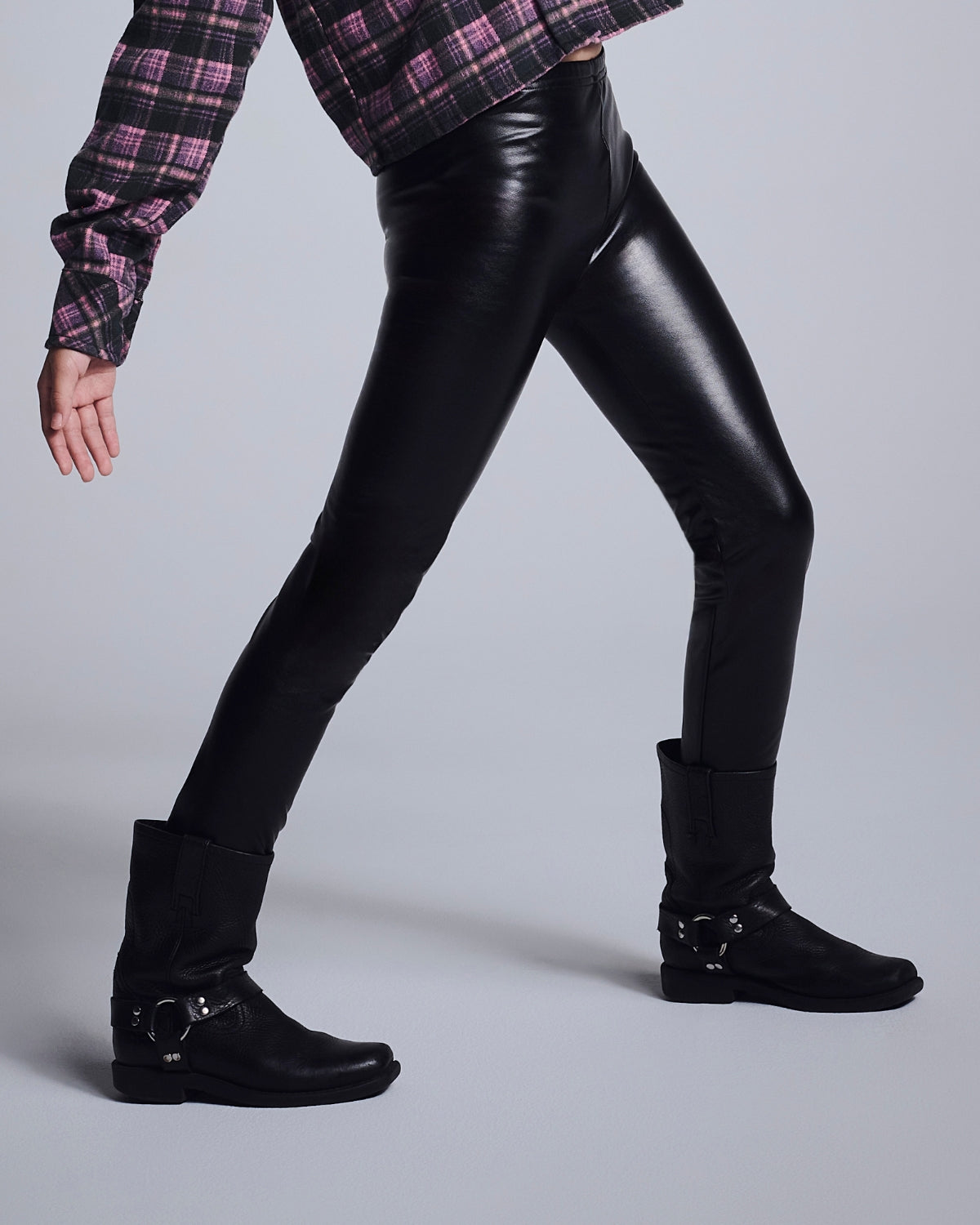Model wearing black leggings from the Girls' Bottoms & Pants collection, styled with a plaid shirt and boots.