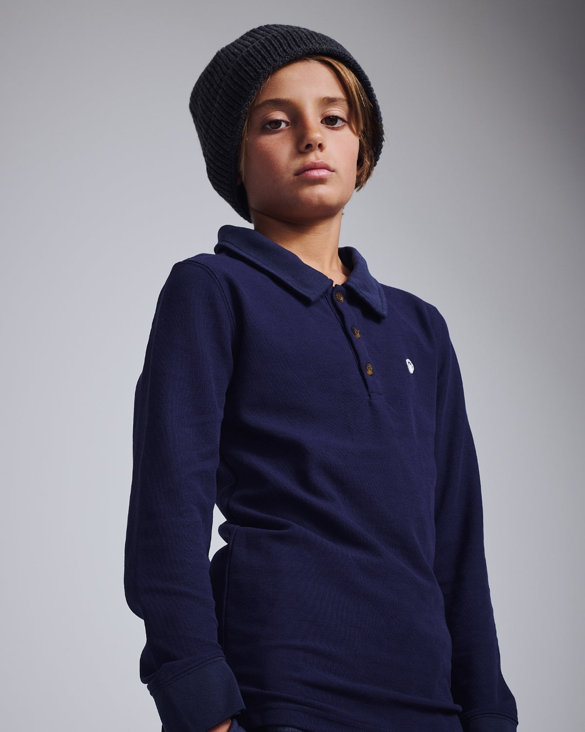 Kids' Winter Hats & Accessories: Boy wearing a stylish black beanie and navy long-sleeve polo.