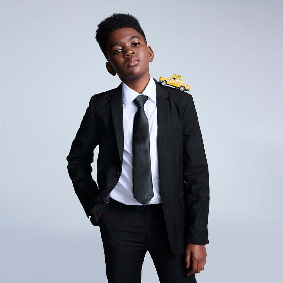 Boys' Black Suits collection featuring a stylish boy in a black suit with a playful toy car on his shoulder.