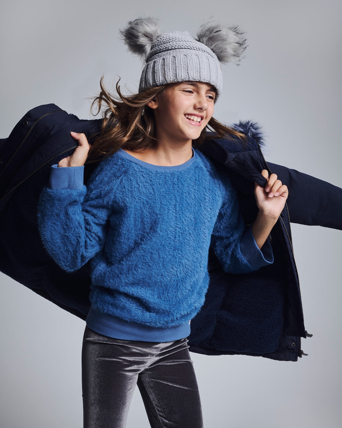 Stylish girl in a chic suit holds a vibrant gift, surrounded by cozy bookshelves—perfect holiday cheer!