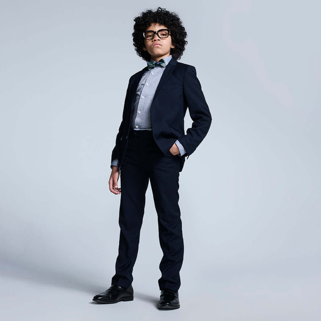 Young boy rocking a stylish navy suit, complete with a bow tie, exuding cool confidence and charm.