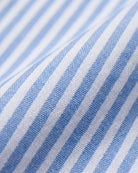 A close-up of a blue and white striped fabric with a visible woven texture and soft folds.