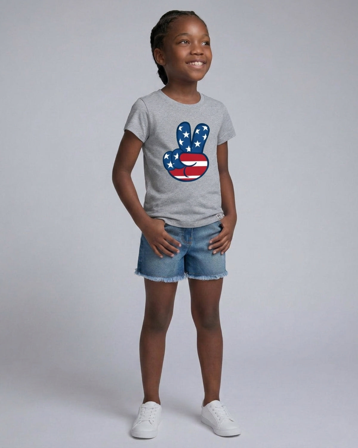 Young girl wearing a gray t-shirt with a peace sign design on a plain background