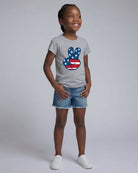 Young girl wearing a gray t-shirt with a peace sign design on a plain background