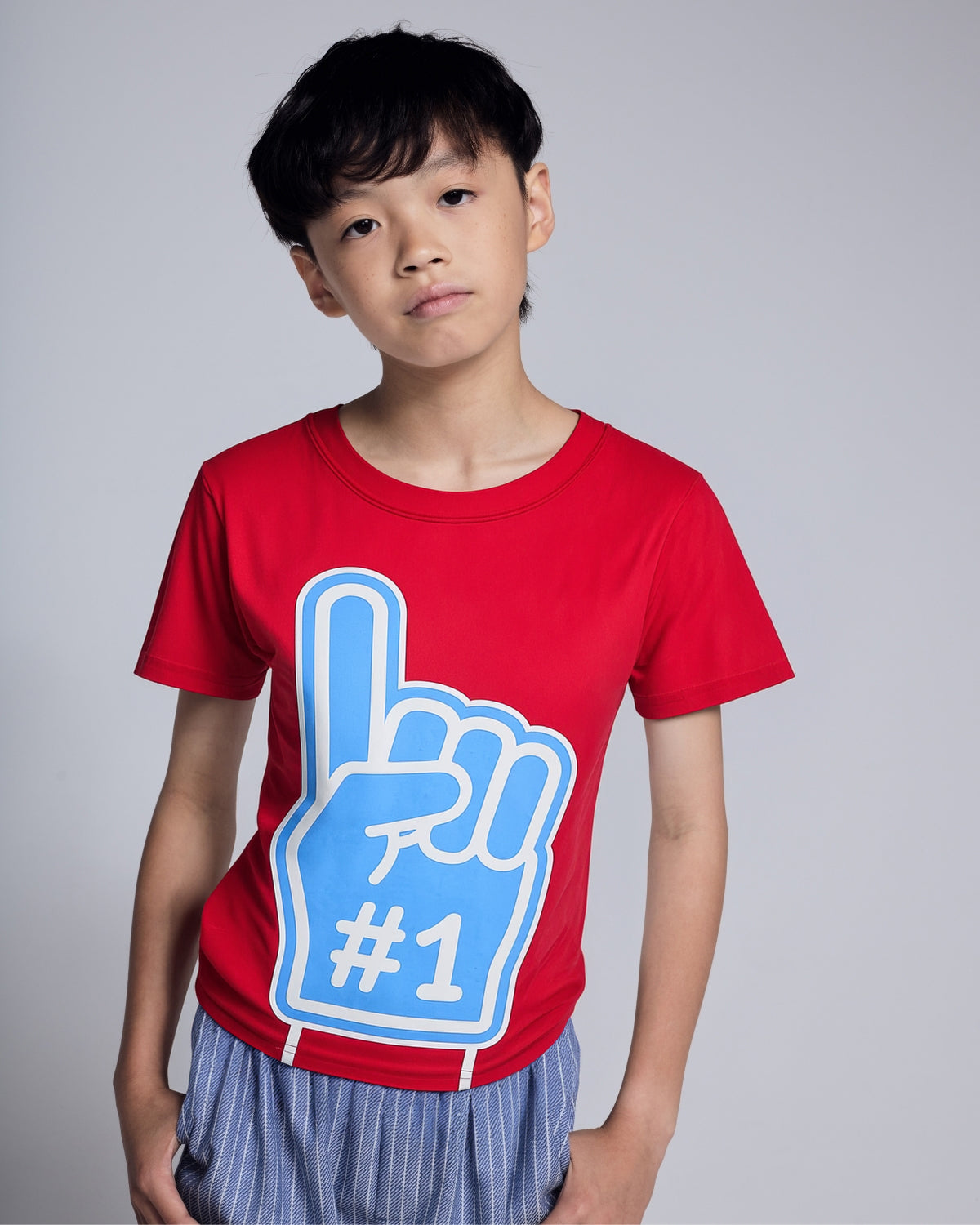 Child wearing a red t-shirt with a blue foam finger design on a plain background