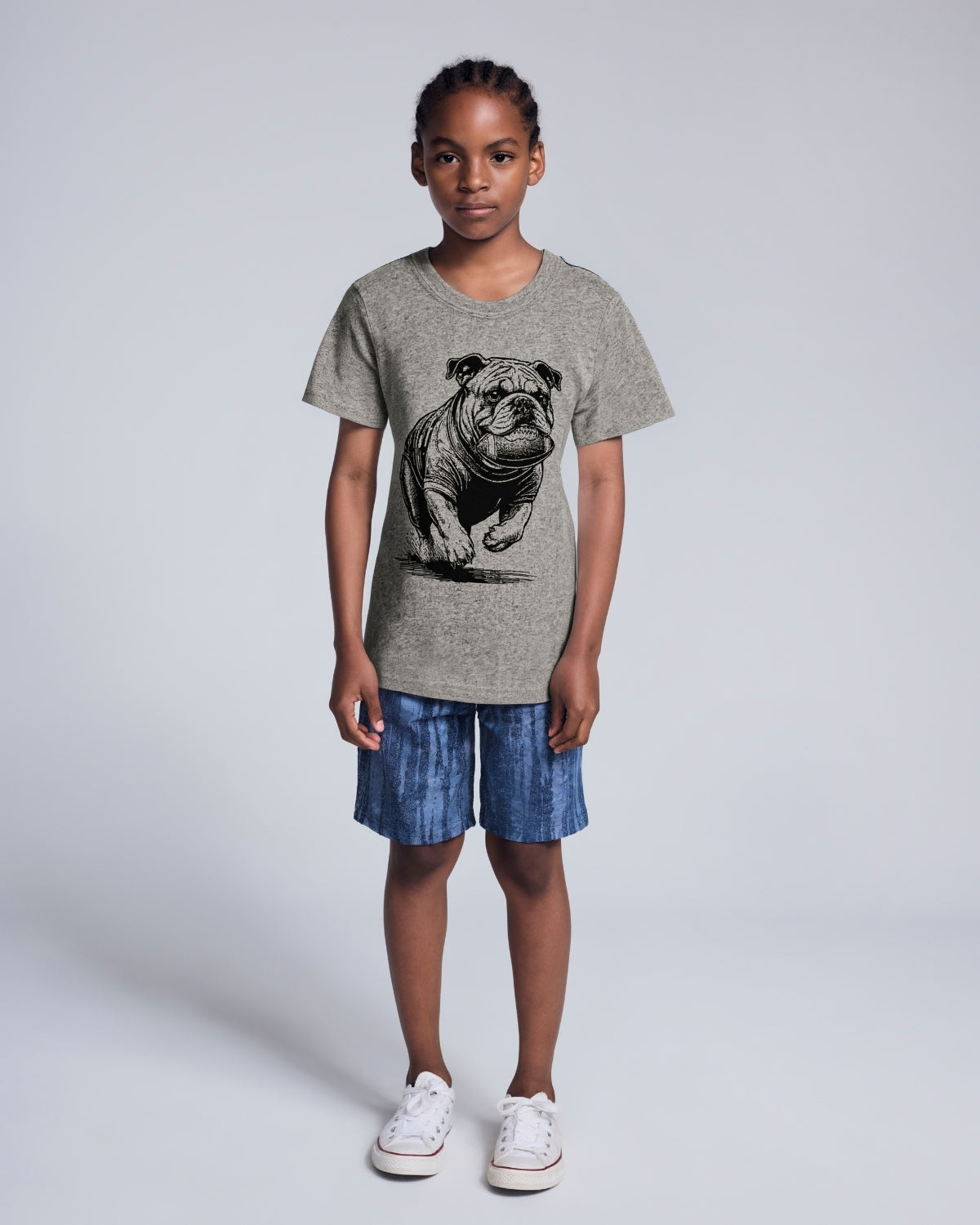 Child wearing a gray t-shirt with a dog graphic and blue shorts on a white background