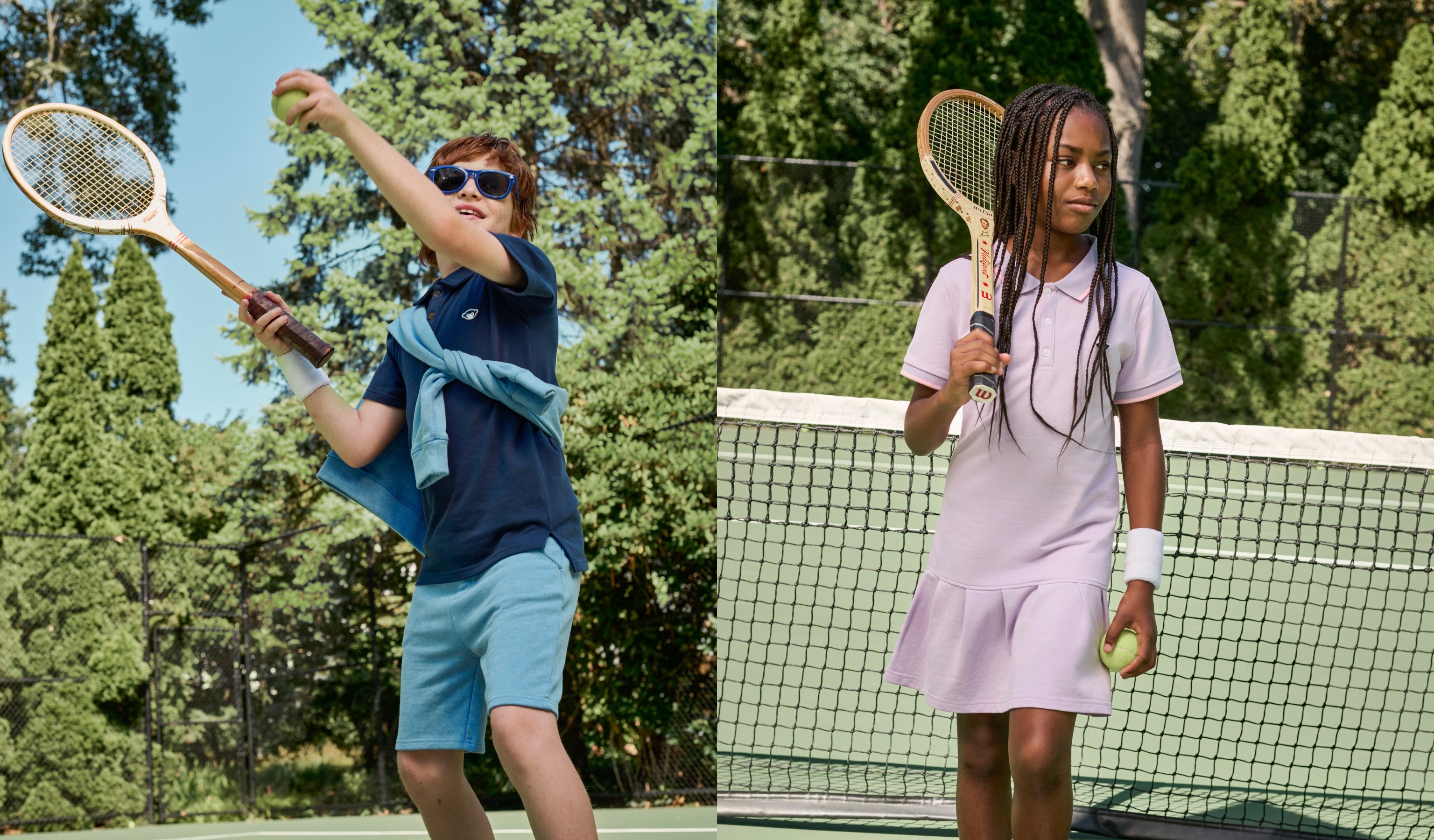 Two children playing tennis on a court with trees in the background.