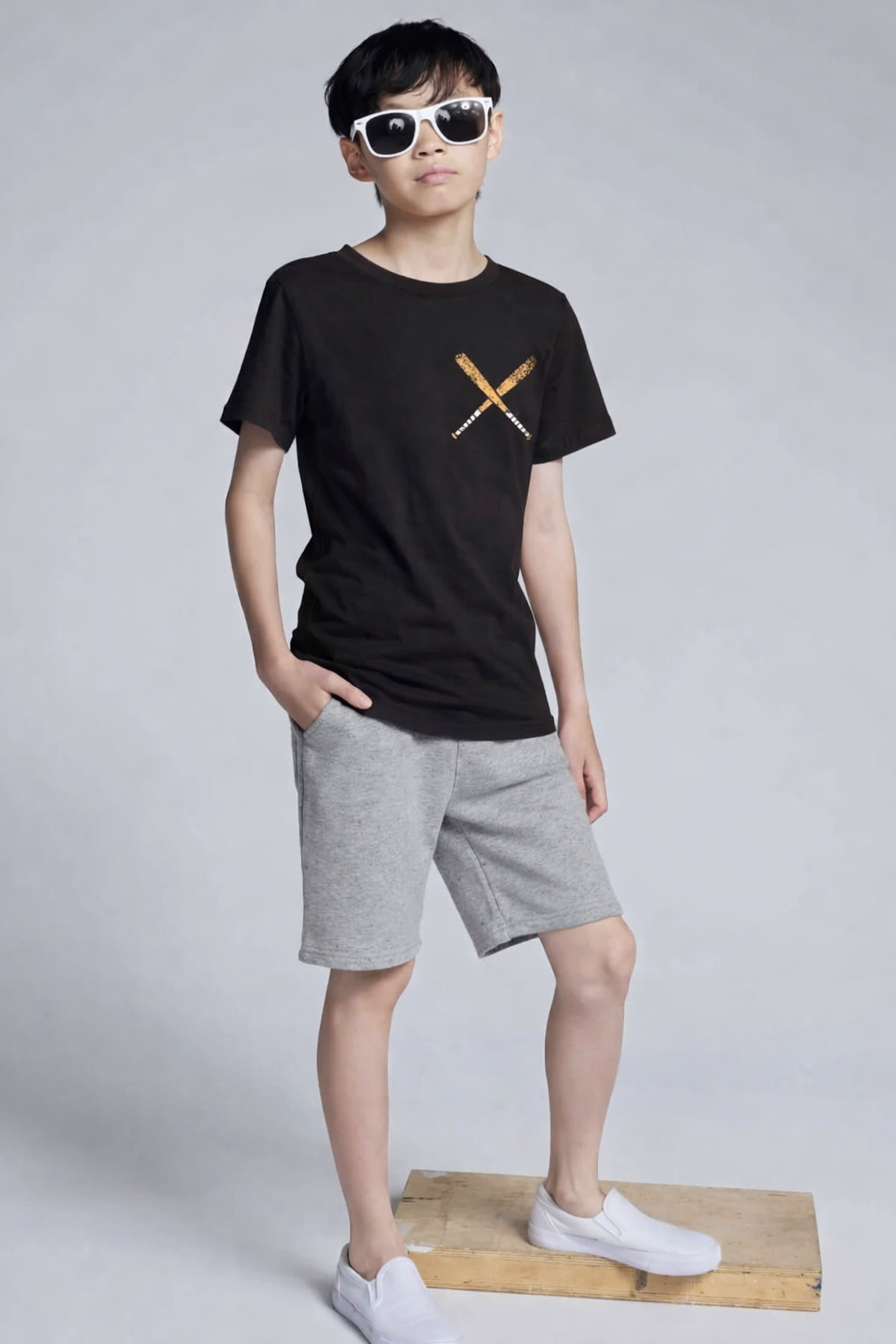 Person wearing a black t-shirt with a logo and gray shorts on a white background