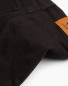 Close-up view of the back of Black Commuter Twill Pants showcasing the logo patch and fabric texture.