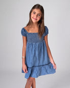 Young girl wearing a blue dress against a plain background