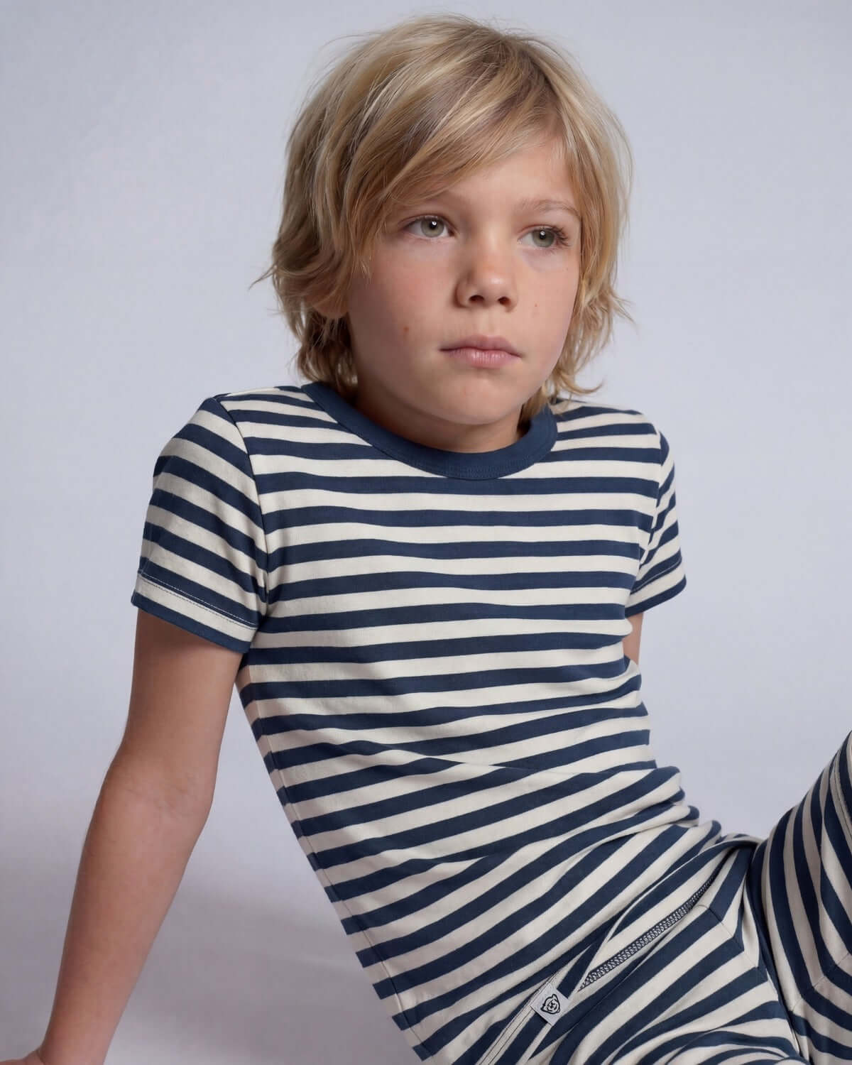 Child wearing a blue and white striped shirt against a plain background