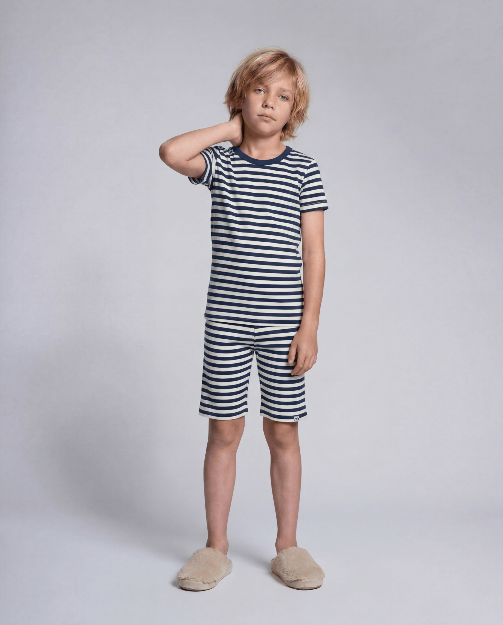 Child wearing a navy and white striped outfit on a plain background