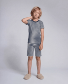 Child wearing a navy and white striped outfit on a plain background