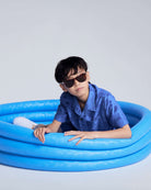 Boy wearing Cobalt Blue Terry Resort Shirt in a blue inflatable pool, stylish and ready for summer fun.
