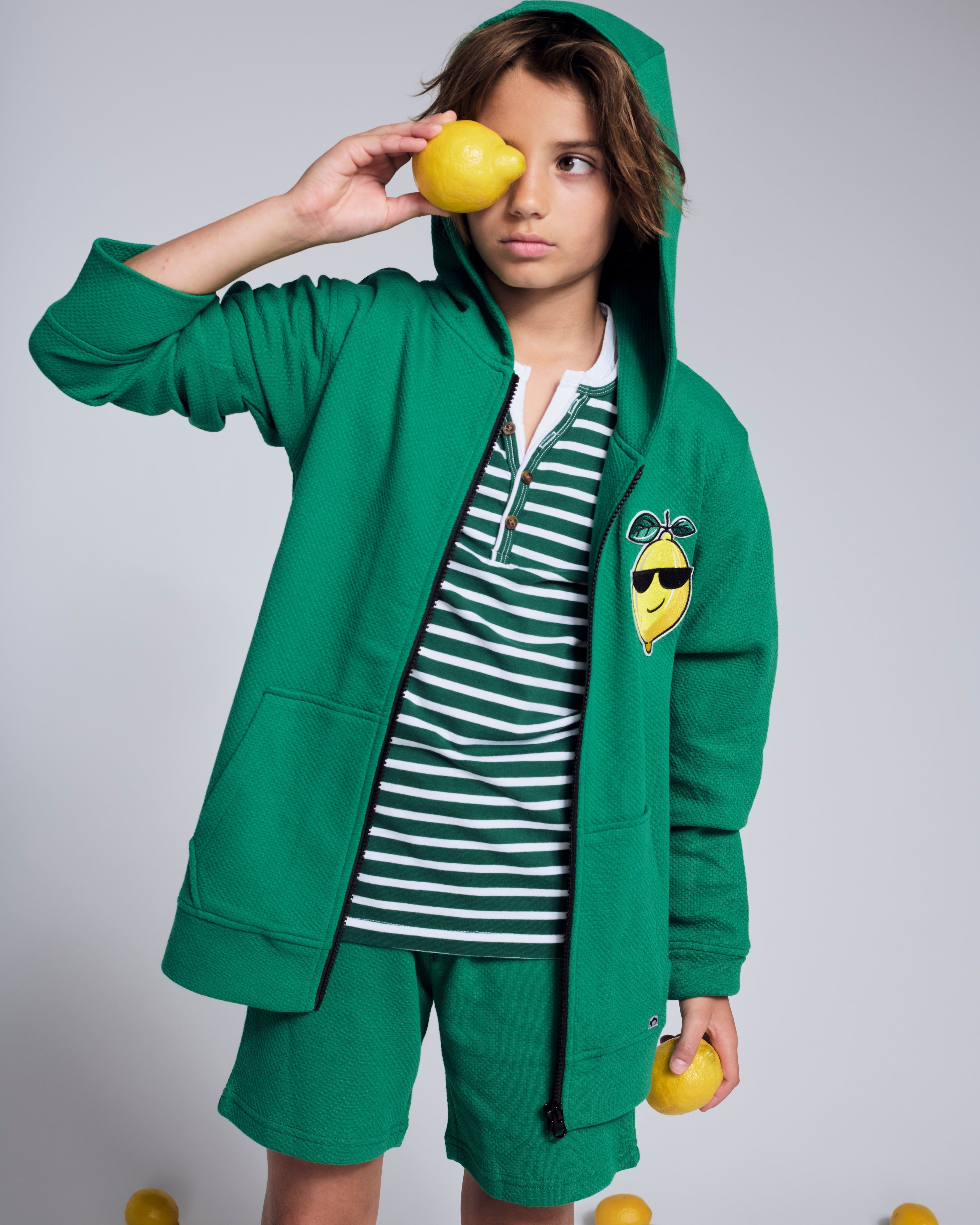 Cool Lemon Strivers Hoodie worn by a child holding a lemon, featuring a cool lemon graphic patch and a zip-up design.