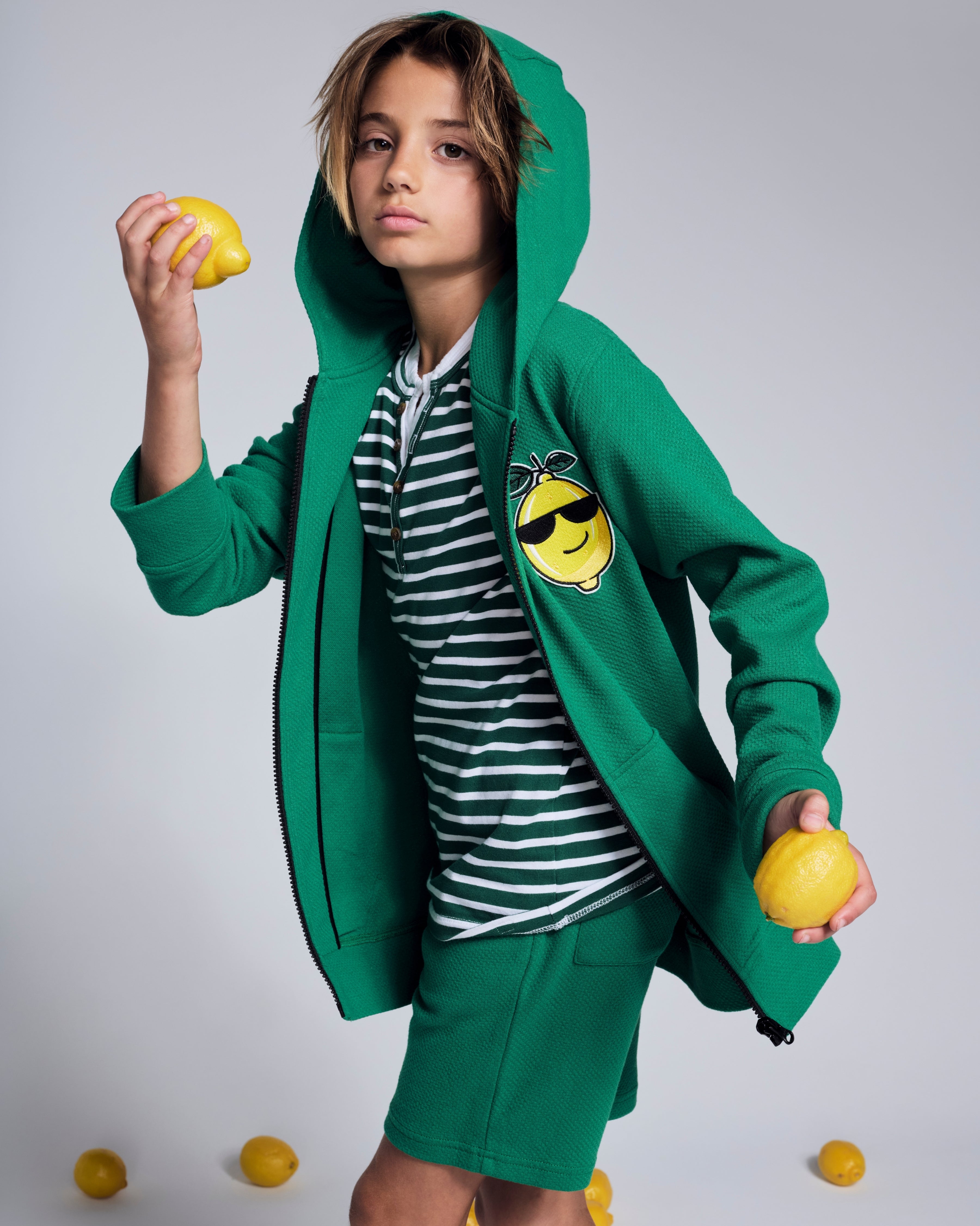Cool Lemon Strivers Hoodie worn by a child holding lemons, showcasing a playful lemon graphic and vibrant green color.