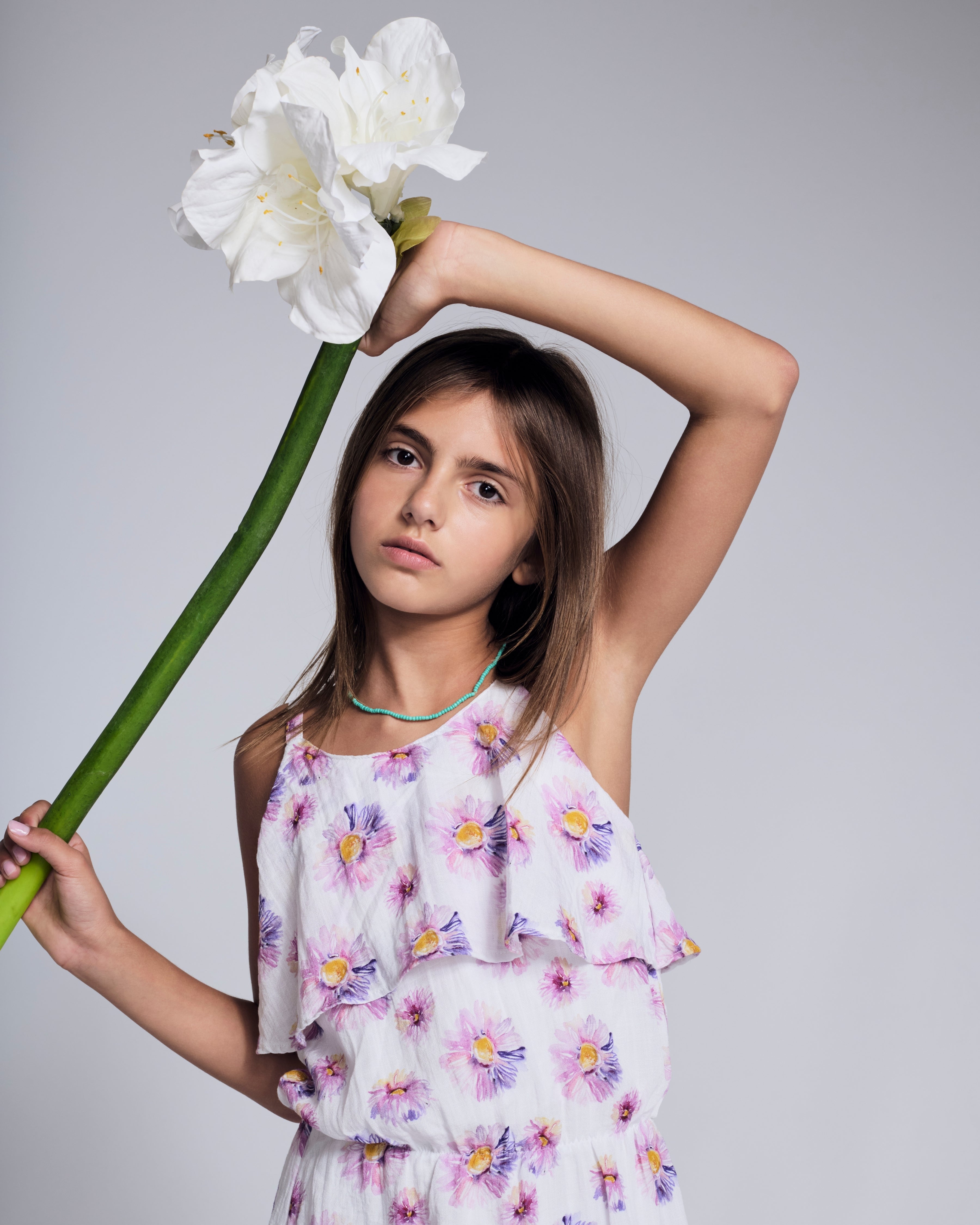 Girl holding a large flower while wearing the Daisies Leah Layered Dress with floral print and layered details.