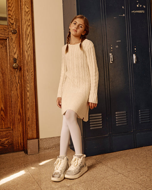 a girl in a white dress and white tights standing in front of lockers