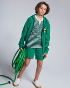 Garden Green Stripe Hilltop Henley styled with a green hoodie and shorts, ideal for casual spring outings.