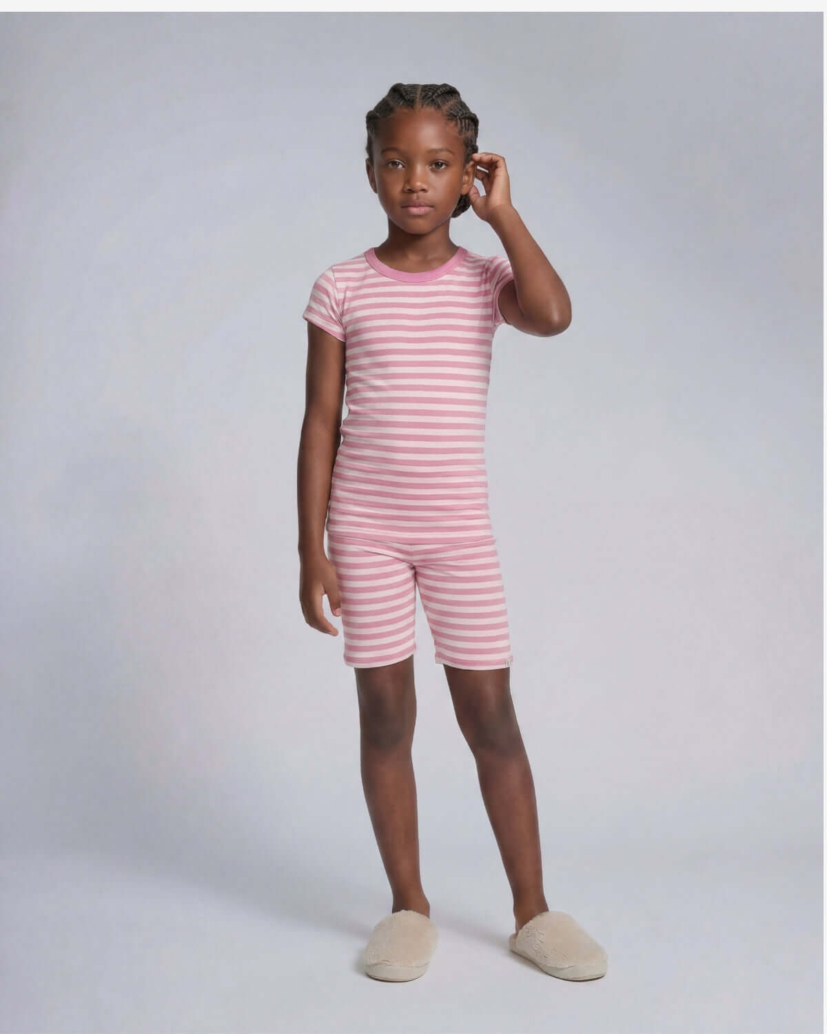 Child wearing a pink and white striped outfit on a plain background