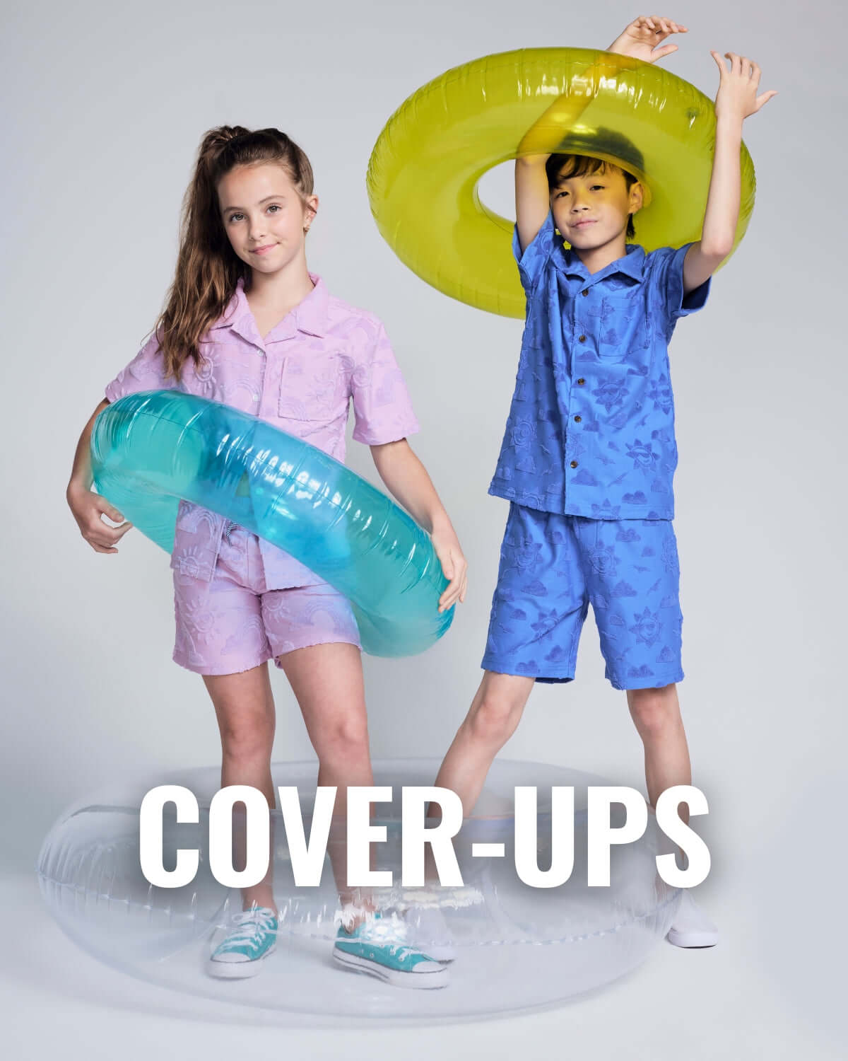 Two kids wearing high-quality cover-ups with inflatable rings, perfect for summer fun in stylish clothing.