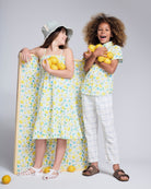 Two kids in a Lemon Zest Day Party Shirt surrounded by lemons, showcasing a fun summer vibe.