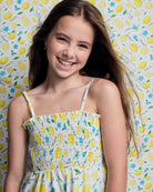 Girl smiling in the Lemon Zest Madison Dress against a lemon-patterned background.