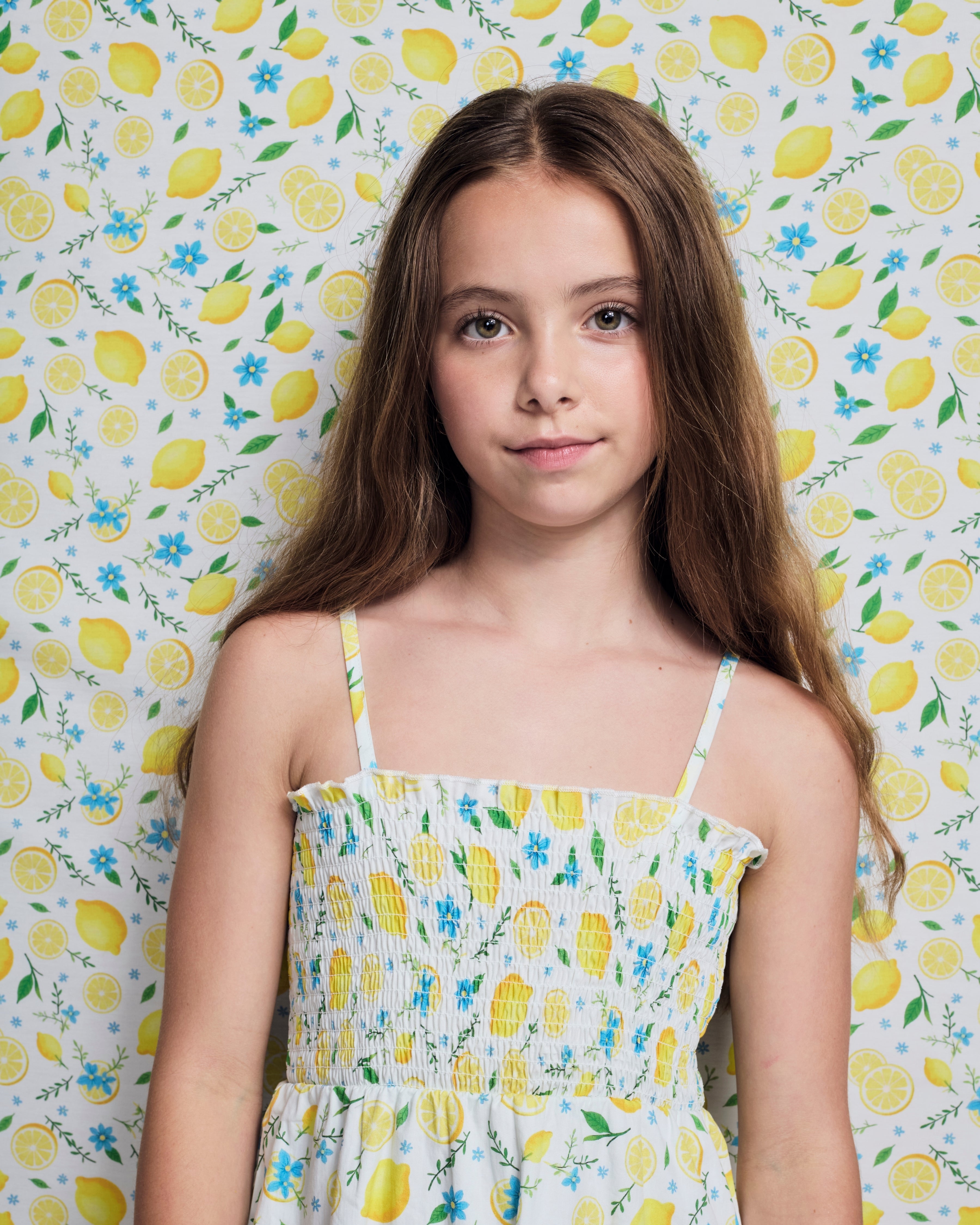 Girl wearing the Lemon Zest Madison Dress with lemon print background.