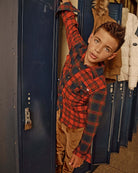 A playful boy peeking out of a school locker, wearing a red plaid shirt and British Khaki Cord Club Pants.