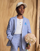 A child wearing a Linen Canopy Stripe Club Blazer and matching trousers, holding flowers for a stylish spring look.