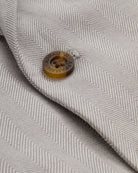 Close-up of button detail on the Linen Warm Grey Sports Jacket with herringbone pattern.