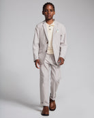 A boy wearing a Linen Warm Grey Sports Jacket paired with light pants and a polo, perfect for spring occasions.