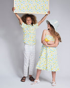 Kids wearing colorful lemon-print outfits, featuring the Linen White Windowpane Resort Pant and a matching dress.