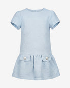 A light blue short-sleeve dress with a textured fabric, featuring a peplum waist and two front pockets with decorative pearl-like buttons.