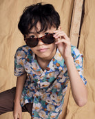 A boy wearing a Painters Garden Camp Collar Shirt and sunglasses, showcasing a stylish summer look.