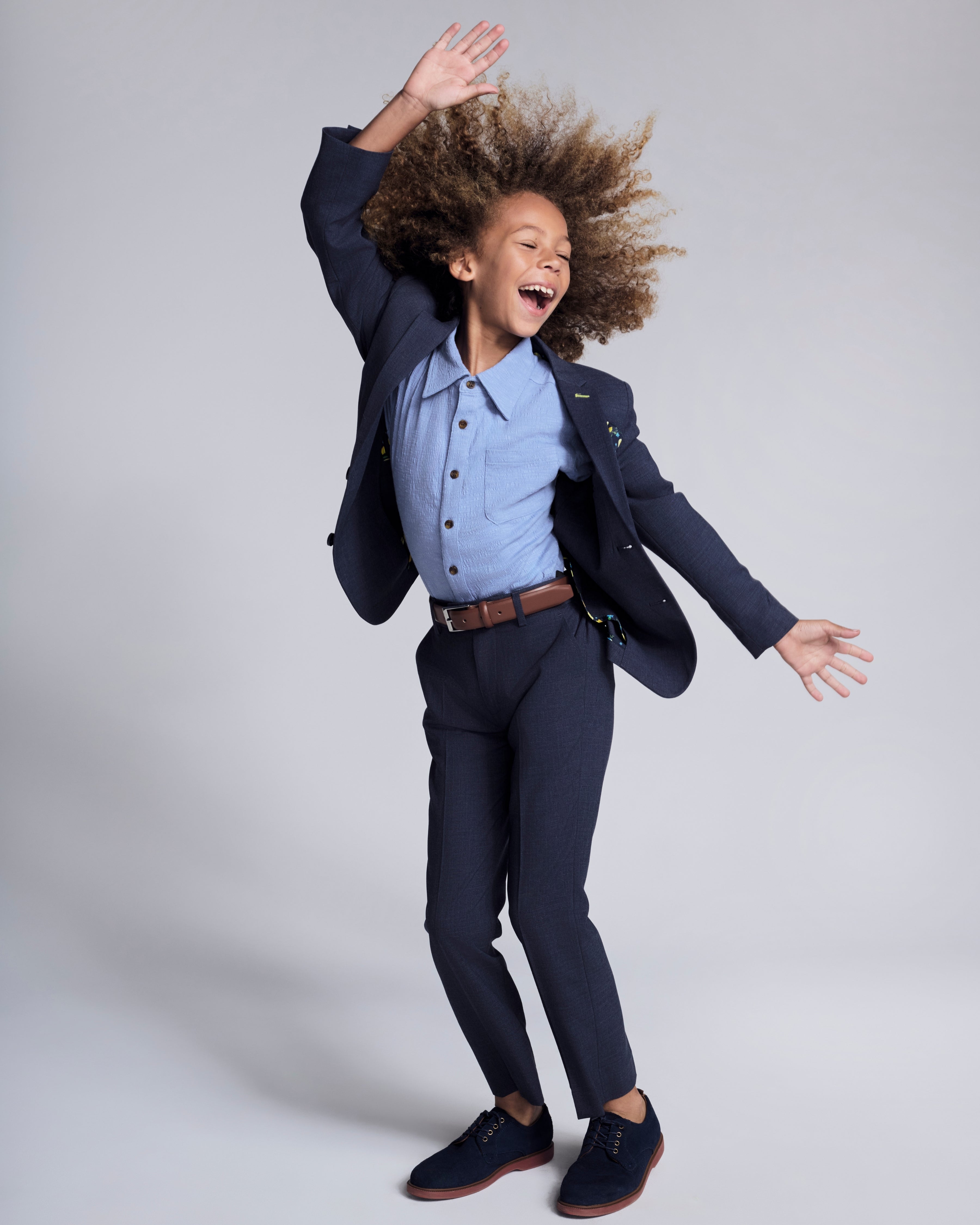 Child wearing a Peacoat Stretchy Mod Suit Pant, styled with a cheerful pose and a blue shirt, showcasing comfort and style.