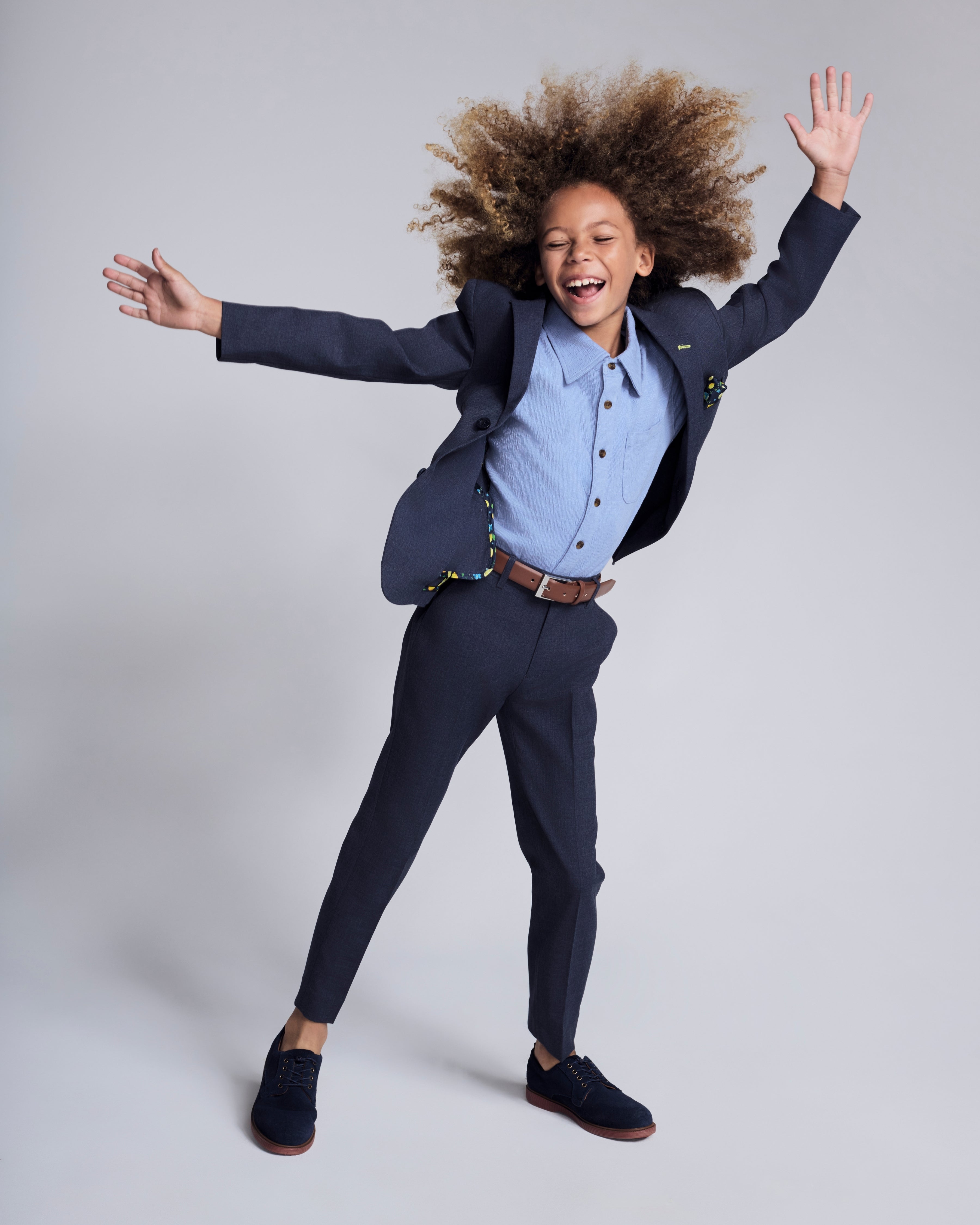Child wearing Peacoat Stretchy Mod Suit Pant with a blazer, showcasing comfort and style in a playful pose.